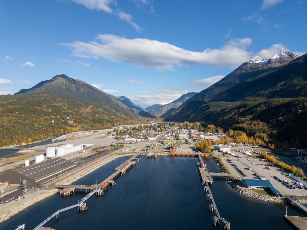 Aerial view of a town on the water with mountains surrounding it.